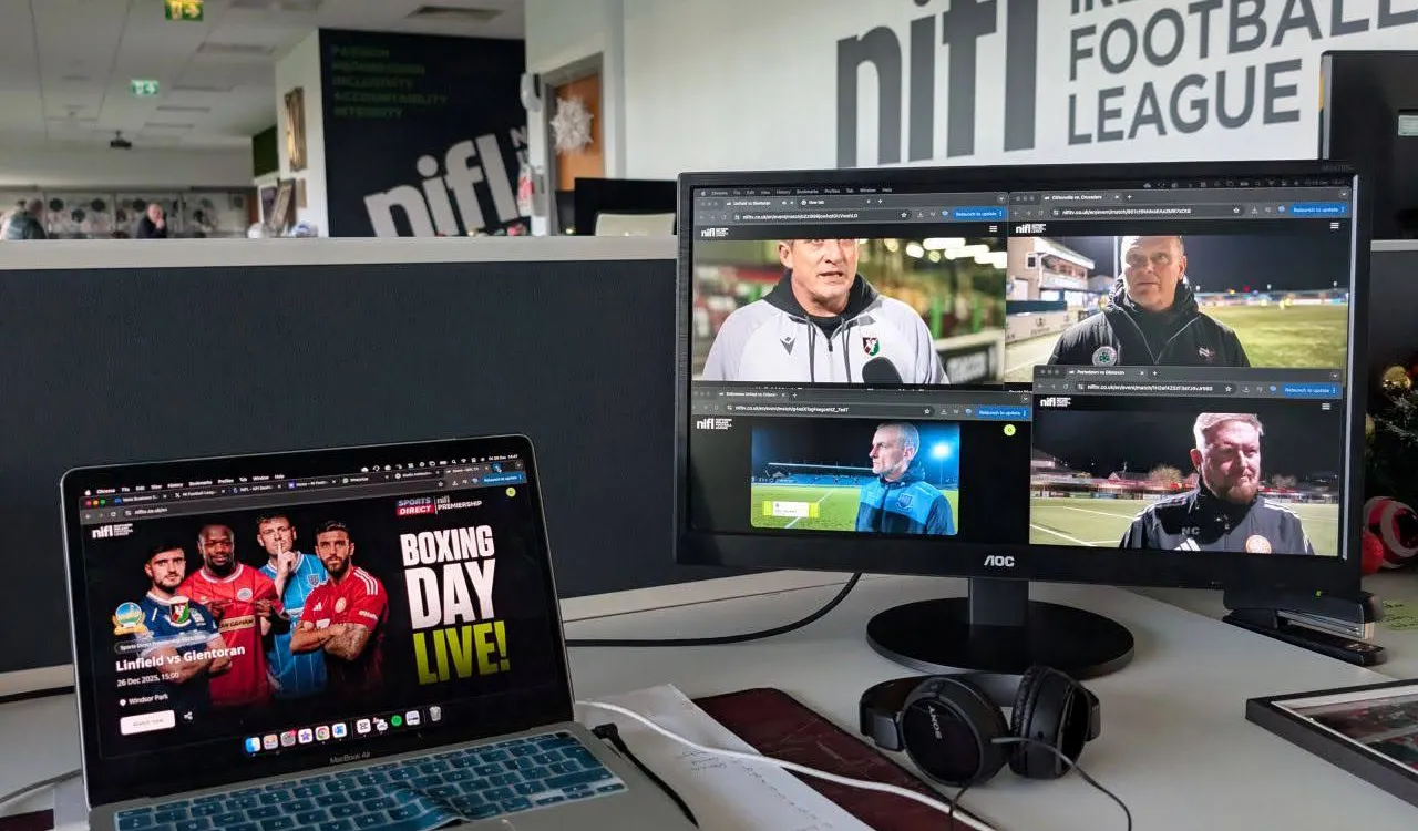 A laptop showing the NIFL TV Boxing Day Live page next to a monitor with four live match feeds, in the NIFL office